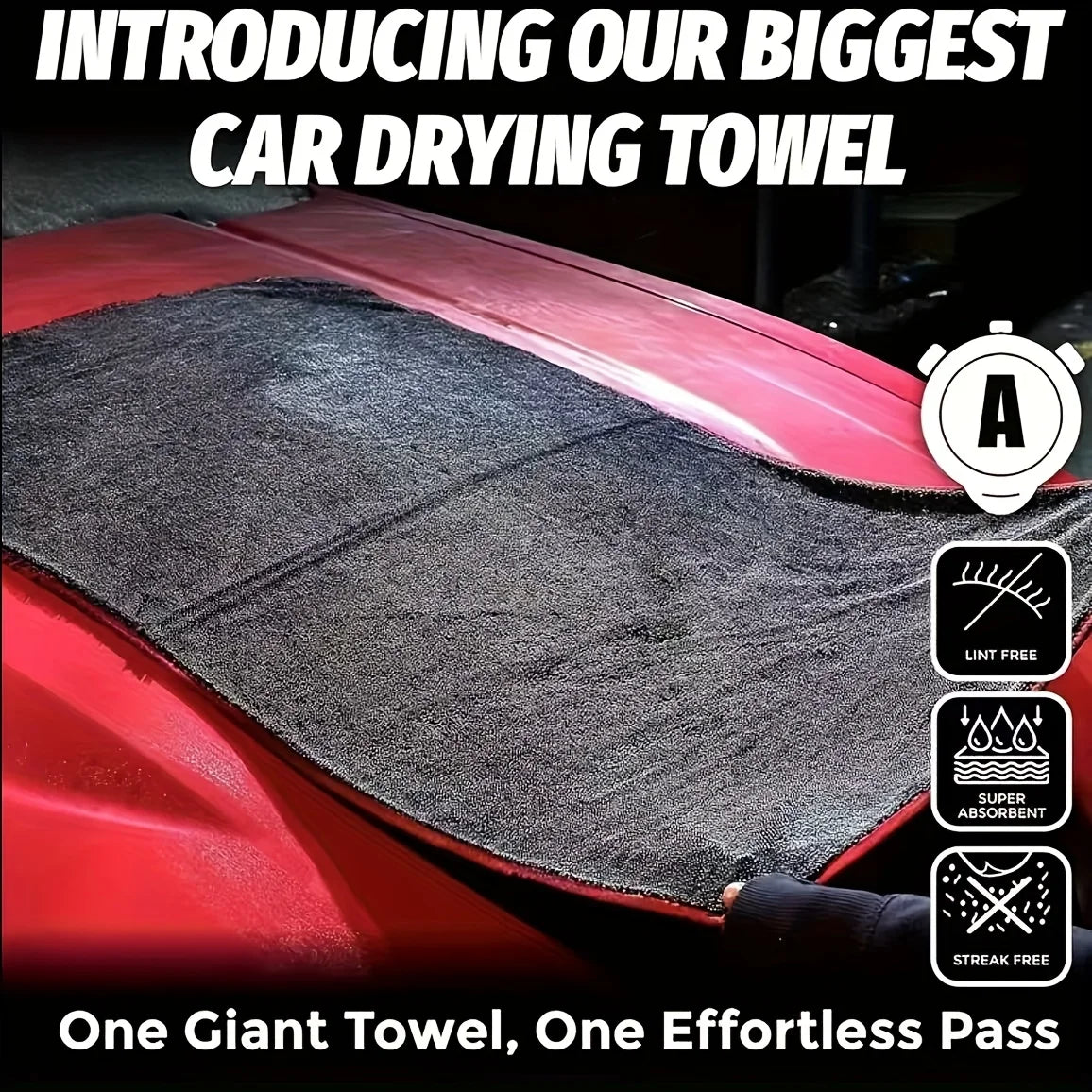 A close-up view of a large black microfiber car drying towel being used on a red car surface.