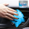 A hand is applying a blue reusable cleaning gel to the interior vents of a car dashboard.
