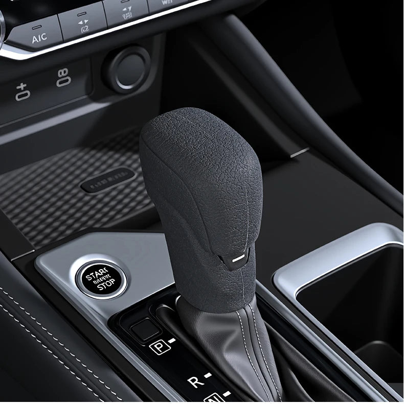 A close-up view of a black non-slip gear shift knob cover installed in a vehicle's interior console.