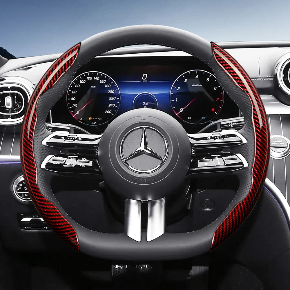 Close-up view of a black steering wheel with red carbon fiber texture accents and a Mercedes-Benz logo.