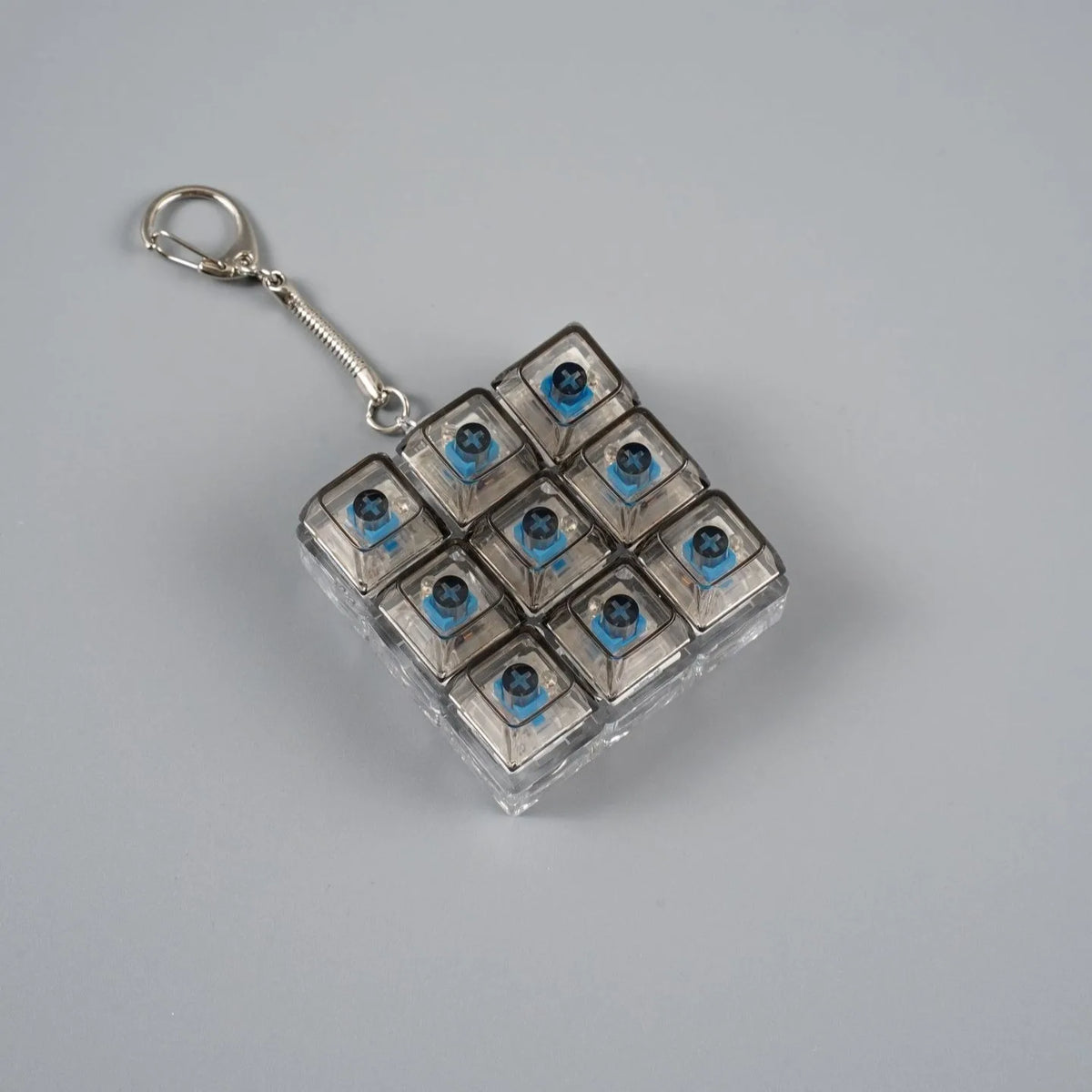 A square metal keychain featuring twelve blue LED lights arranged in a grid.
