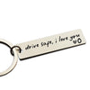 A stainless steel keychain tag engraved with the message drive safe i love you and a heart symbol