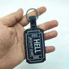 A black gothic keyfob luggage tag with the name HELL and the number 666 is held in a hand.