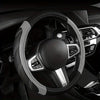 A black steering wheel with a gray leather wrap and silver accents inside a car interior.