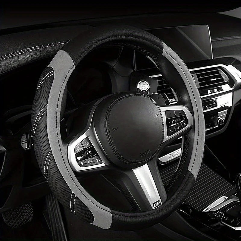 A black steering wheel with a gray leather wrap and silver accents inside a car interior.