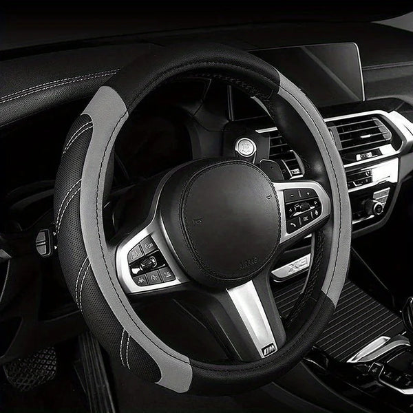 A black steering wheel with a gray leather wrap and silver accents inside a car interior.