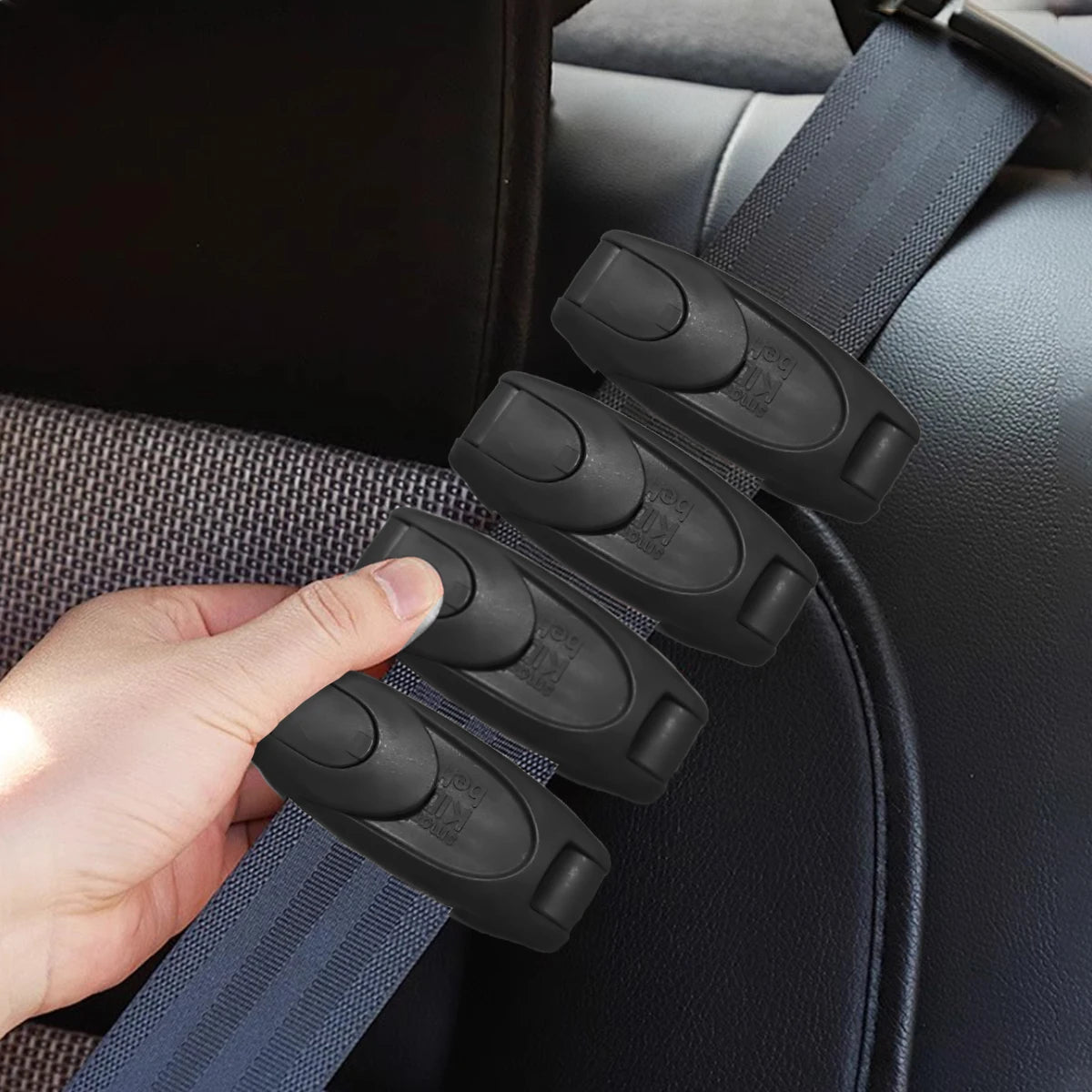 A hand is holding a black comfort-adjustable seat belt clip attached to a dark automotive seat.