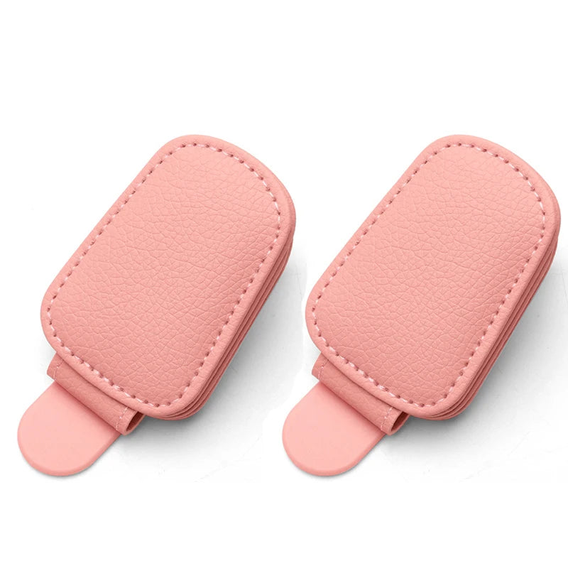 A pair of pink magnetic leather sunglasses holders designed for car sun visors.