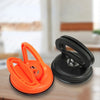 Orange and black car dent glass suction removal tool shown on a wooden surface.