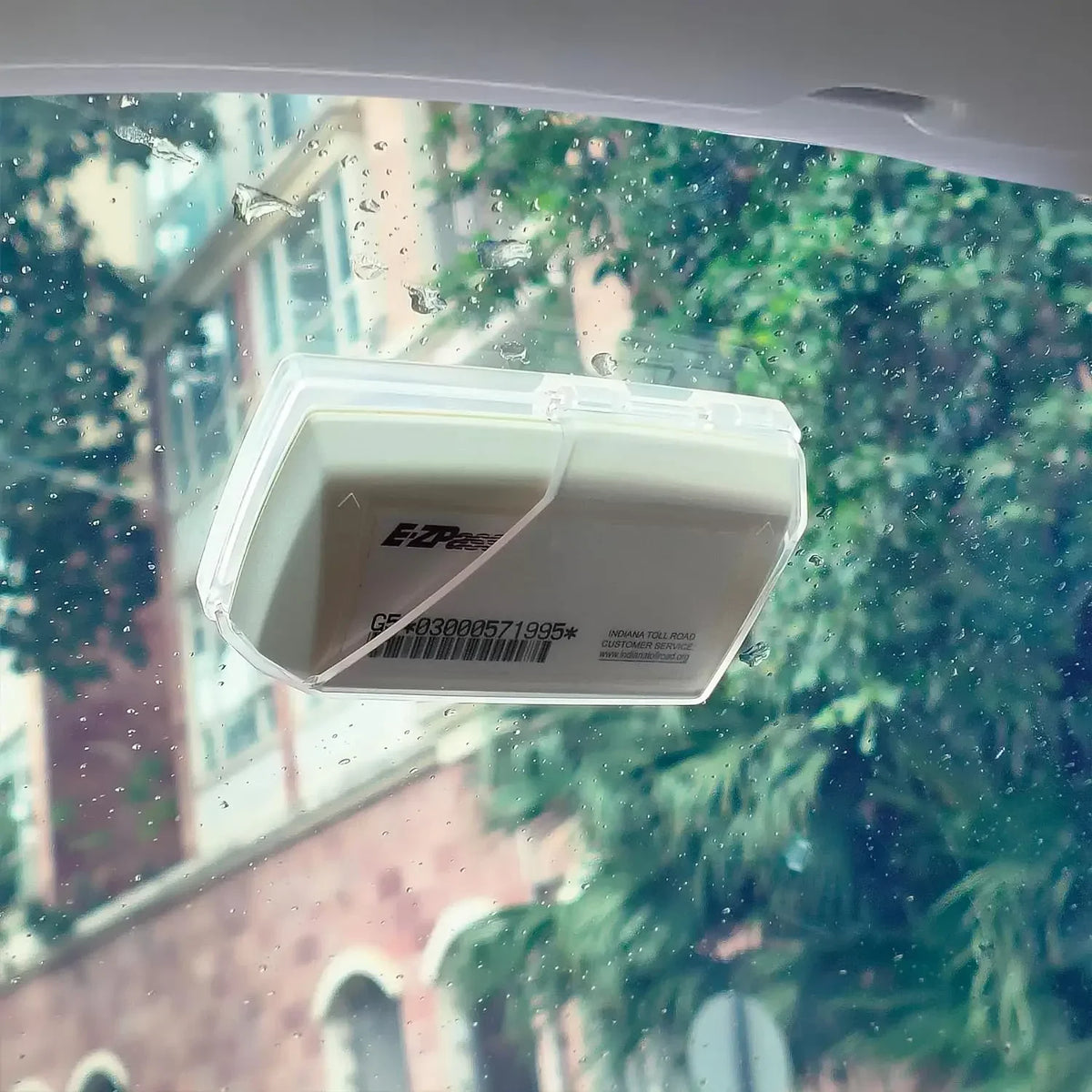 A clear EZ Pass holder is visible on a windshield, showing suction cups and a barcode.