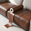 A roll of brown self-adhesive PU leather repair patches is placed on a brown leather sofa cushion.