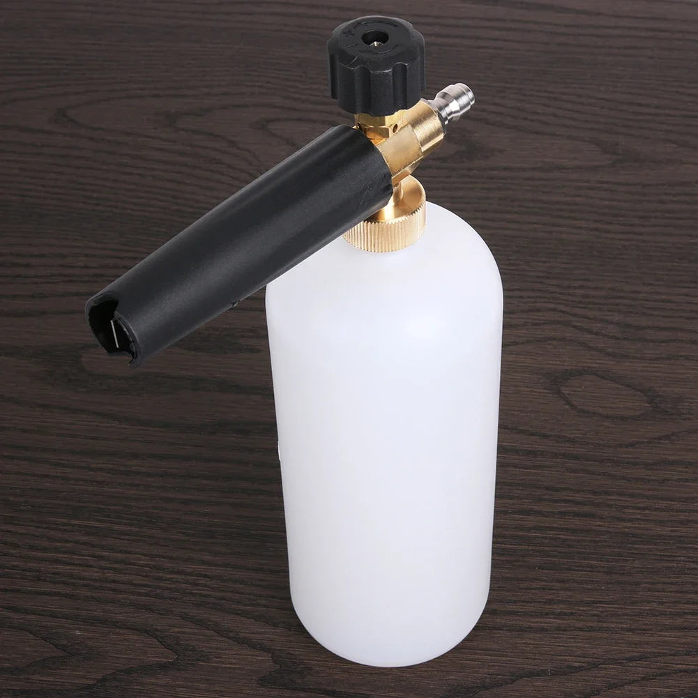 A black high-pressure car cleaning foam gun is shown next to its white bottle on a dark wooden surface.