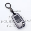 A close-up view of a dark gray universal car key cover with a metal loop and a plastic body.