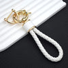 Gold-toned multi-function car key cover with a white braided lanyard resting on a white surface.