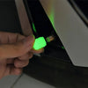 A hand is inserting a green luminous tire valve cap onto a metal fitting for a self-luminous tire valve cap.