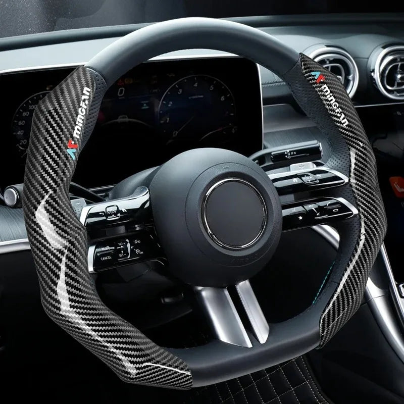 Close-up view of a black steering wheel with a carbon fiber patterned cover and modern controls.