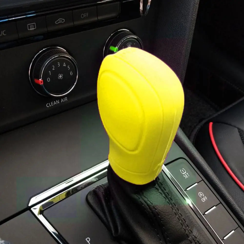 Una cubierta de palanca de cambios de silicona amarilla brillante colocada en la consola interior de un coche.