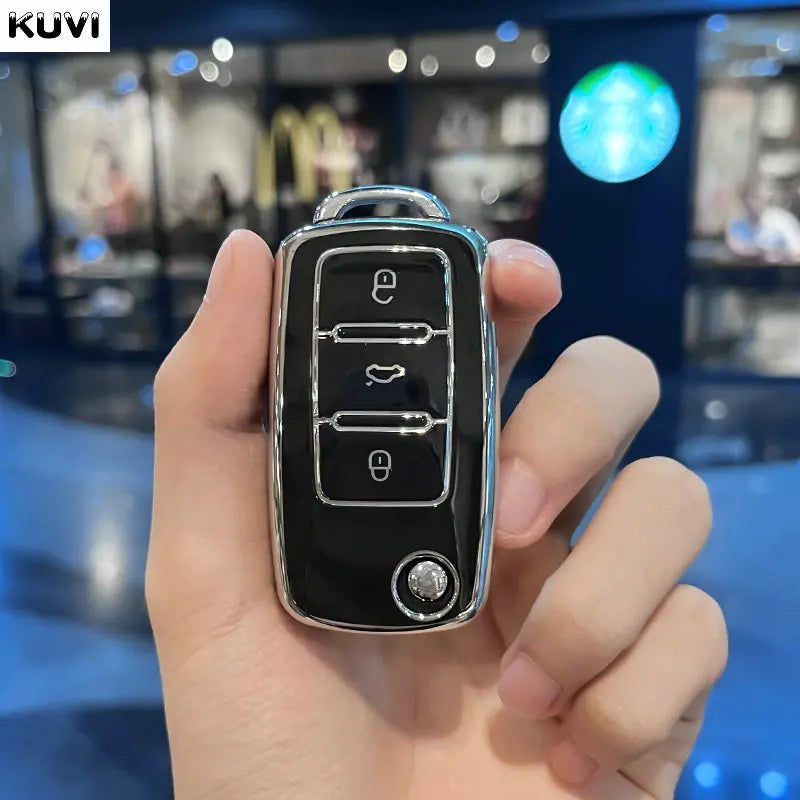 A hand holds a black TPU car key cover for Volkswagen, Skoda, and Seat vehicles.