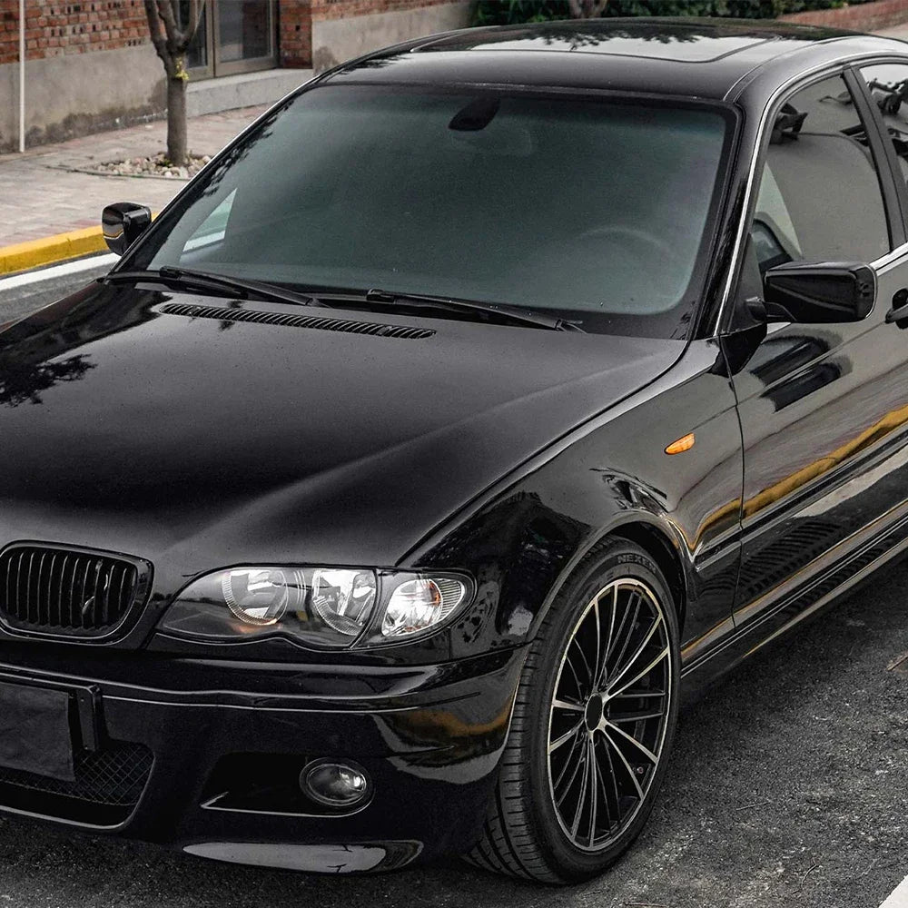 A glossy black sedan parked outdoors with custom wheels and decals.