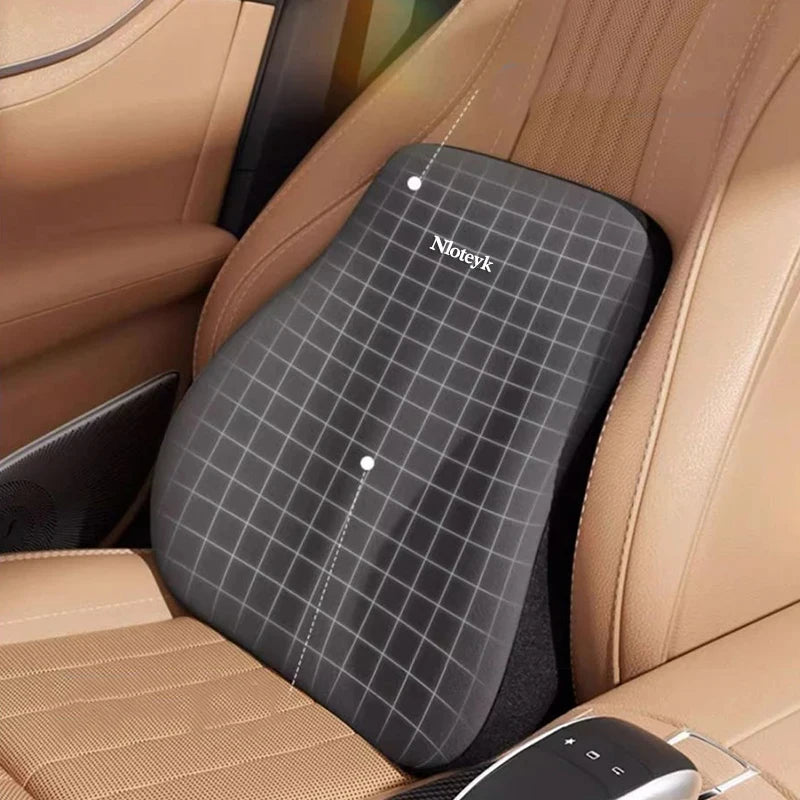 A black ergonomic lumbar support pillow is shown placed in the seat of a car, next to a leather seat cushion.