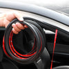 A hand is holding a coil of black and red car door soundproofing seals.