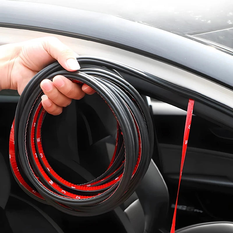 A hand is holding a coil of black and red car door soundproofing seals.