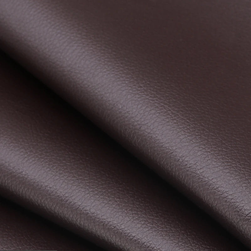 Primer plano de material de cuero PU marrón oscuro mostrando una textura suave y pliegue.