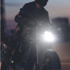 A person is holding a 36W LED motorcycle headlight bulb in a dark setting.