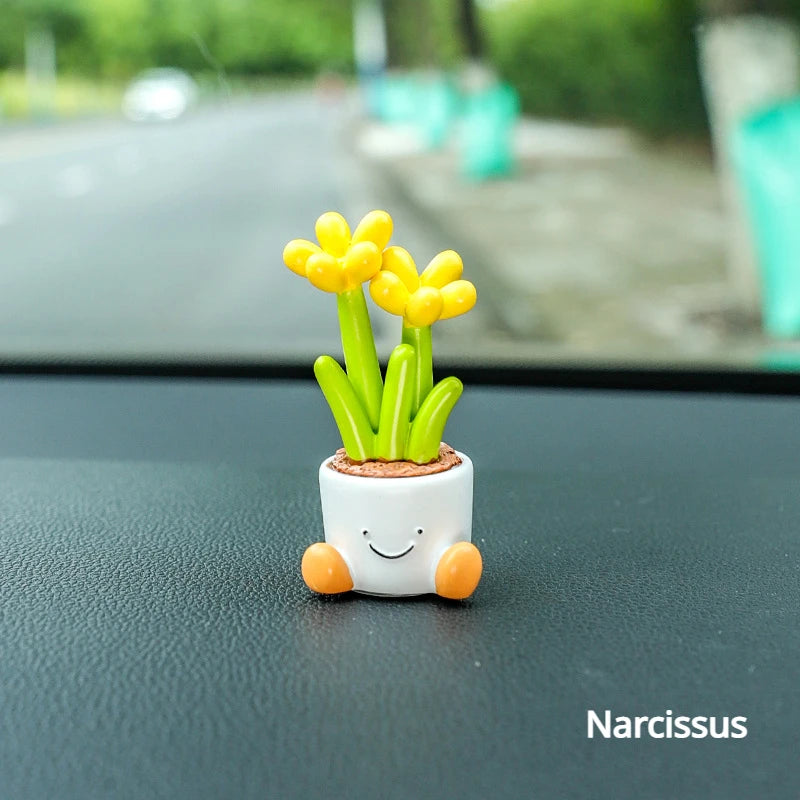 Kleine weiße Harz-Elfen-Auto-Dekoration mit leuchtend gelben Narzissenblumen, die aus grünen Stielen in einer Vase wachsen.