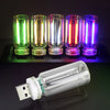 Eine Reihe von acht leuchtenden LED-Röhren in verschiedenen Farben sitzt auf einer schwarzen USB-Ladekarte mit einer klaren G