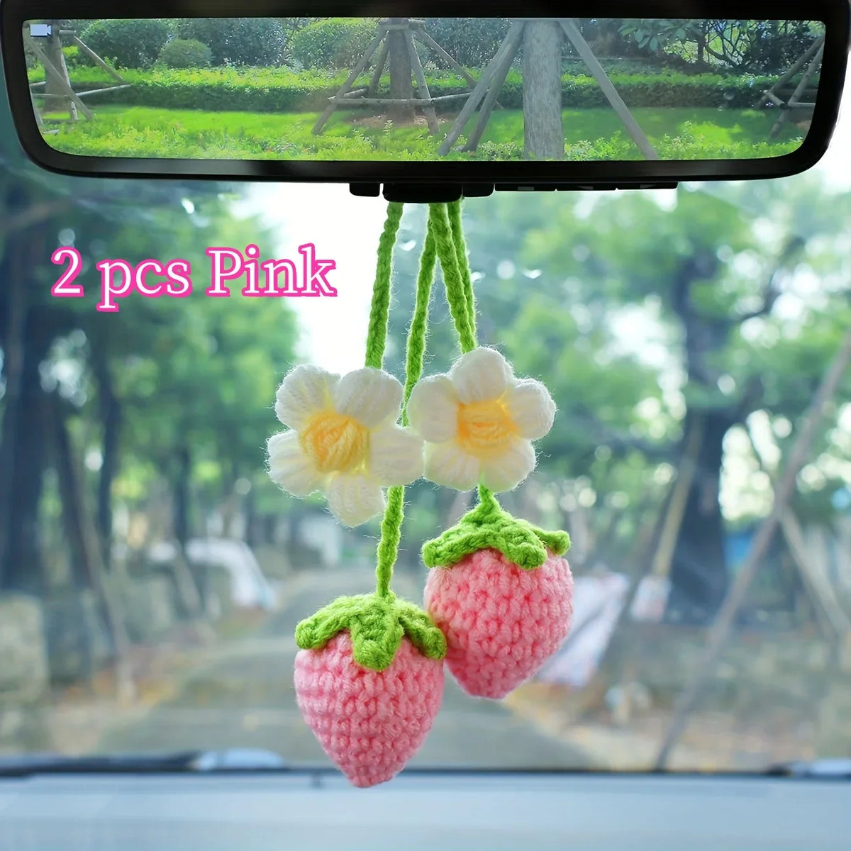 Deux colliers de clés en crochet de fraises roses faits à la main, accrochés devant le pare-brise d'une voiture.