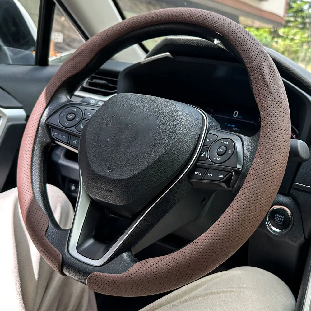 Nahaufnahme einer braunen Leder-Lenkradabdeckung, installiert auf dem Lenkrad eines Autos.