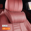 A close-up view of a pink leather car neck pillow with stitching and a dotted pattern.