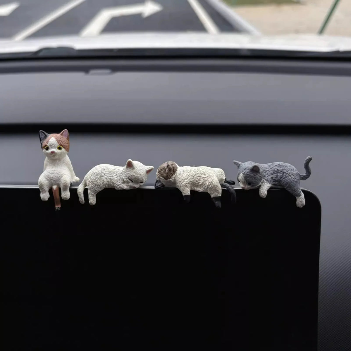 Un set de cuatro pequeñas figuras de gatitos peludos en tonos de gris y blanco sobre una superficie oscura.