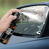 A hand sprays car glass with an anti fog hydrophobic coating spray on a car window.