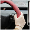 A hand is holding a red perforated steering wheel cover, highlighting its elegant texture and fit.