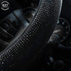 Close-up view of a black crystal rhinestone steering wheel cover on a car interior.