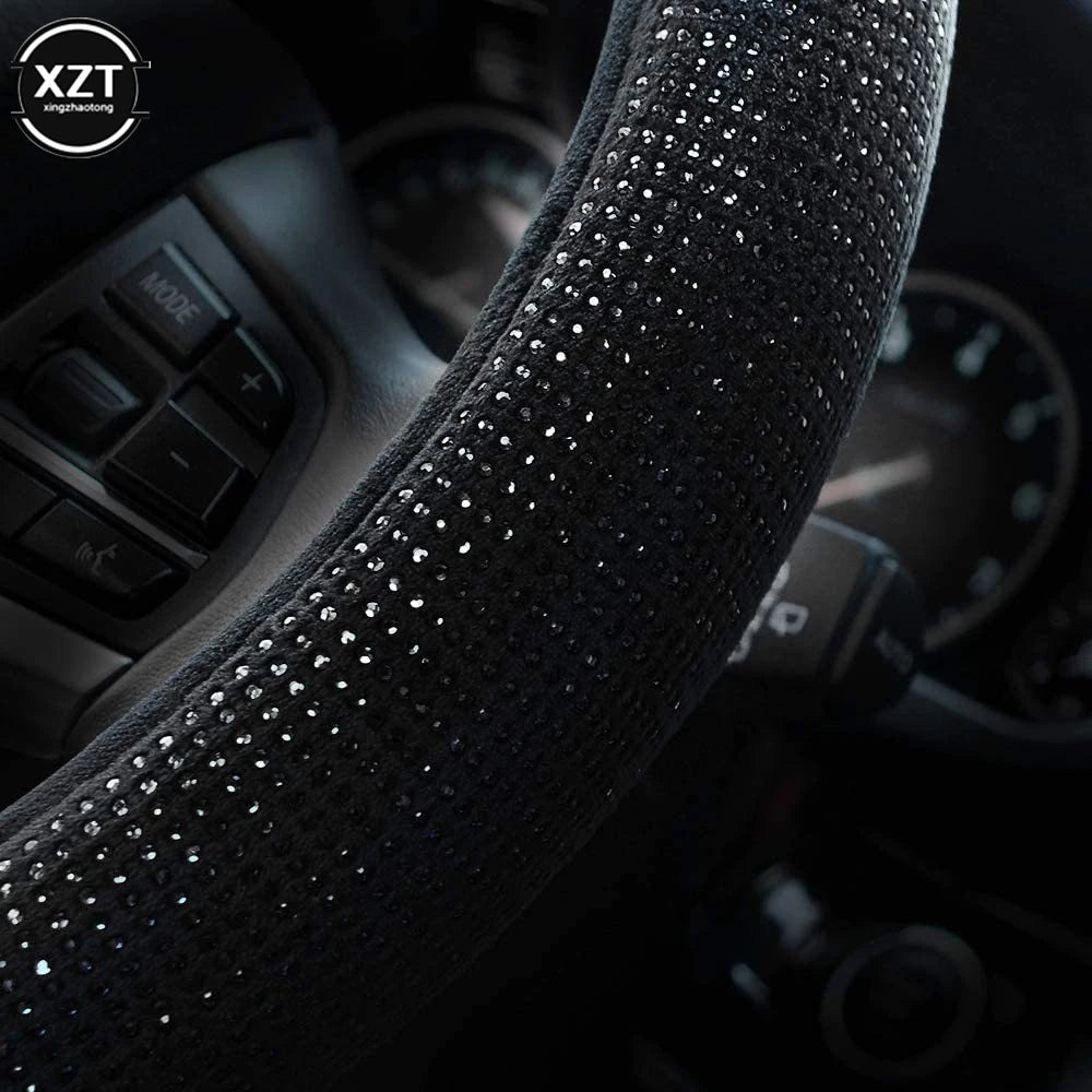 Close-up view of a black crystal rhinestone steering wheel cover on a car interior.