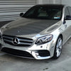 A silver Mercedes-Benz sedan parked outdoors in front of a corrugated metal garage door.