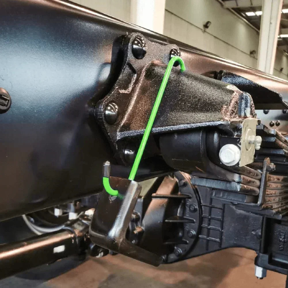 Close-up view of a car brake caliper hanger assembly with a green wire and mounting brackets.