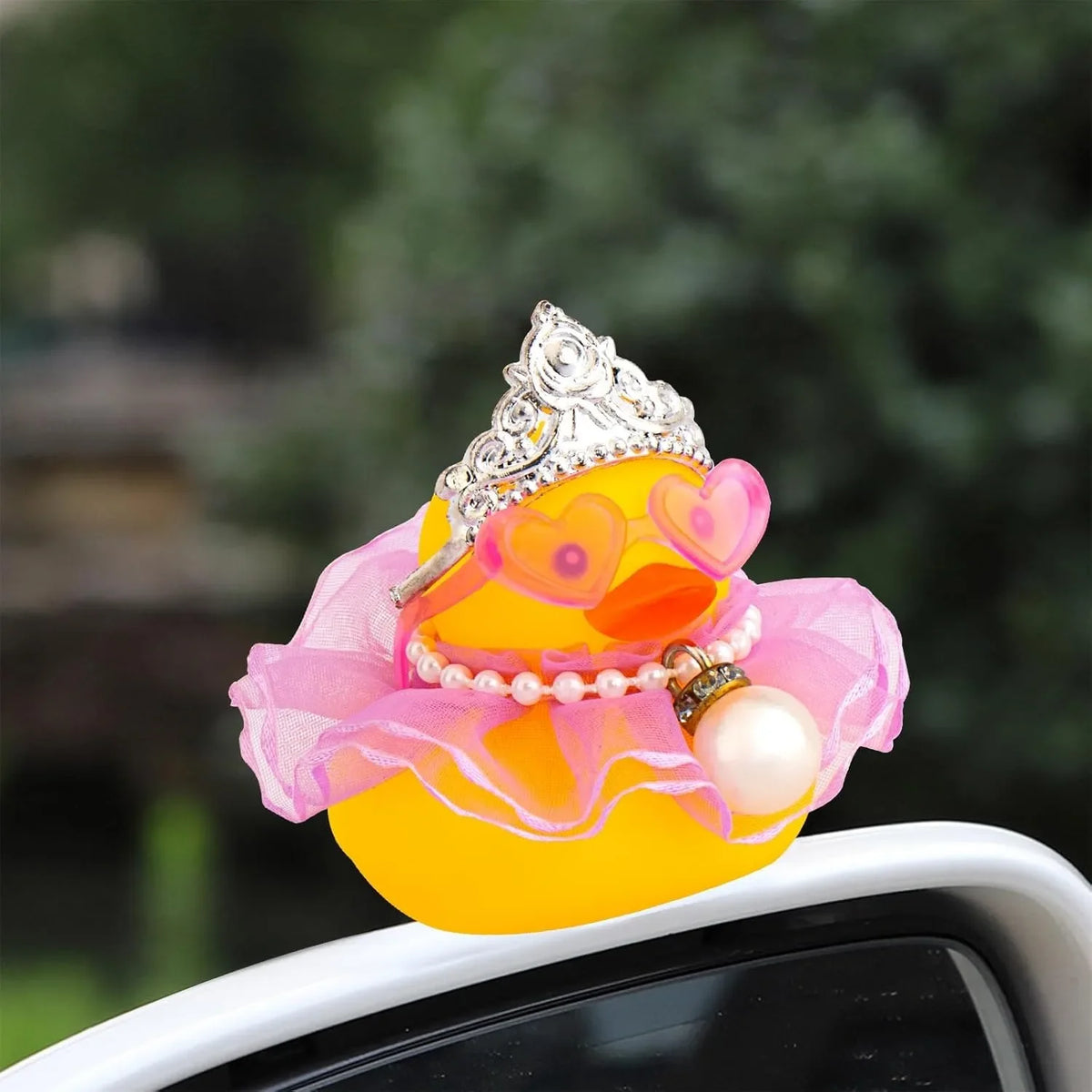 A decorative rubber duck in yellow with a pink ruffled collar and a silver crown.