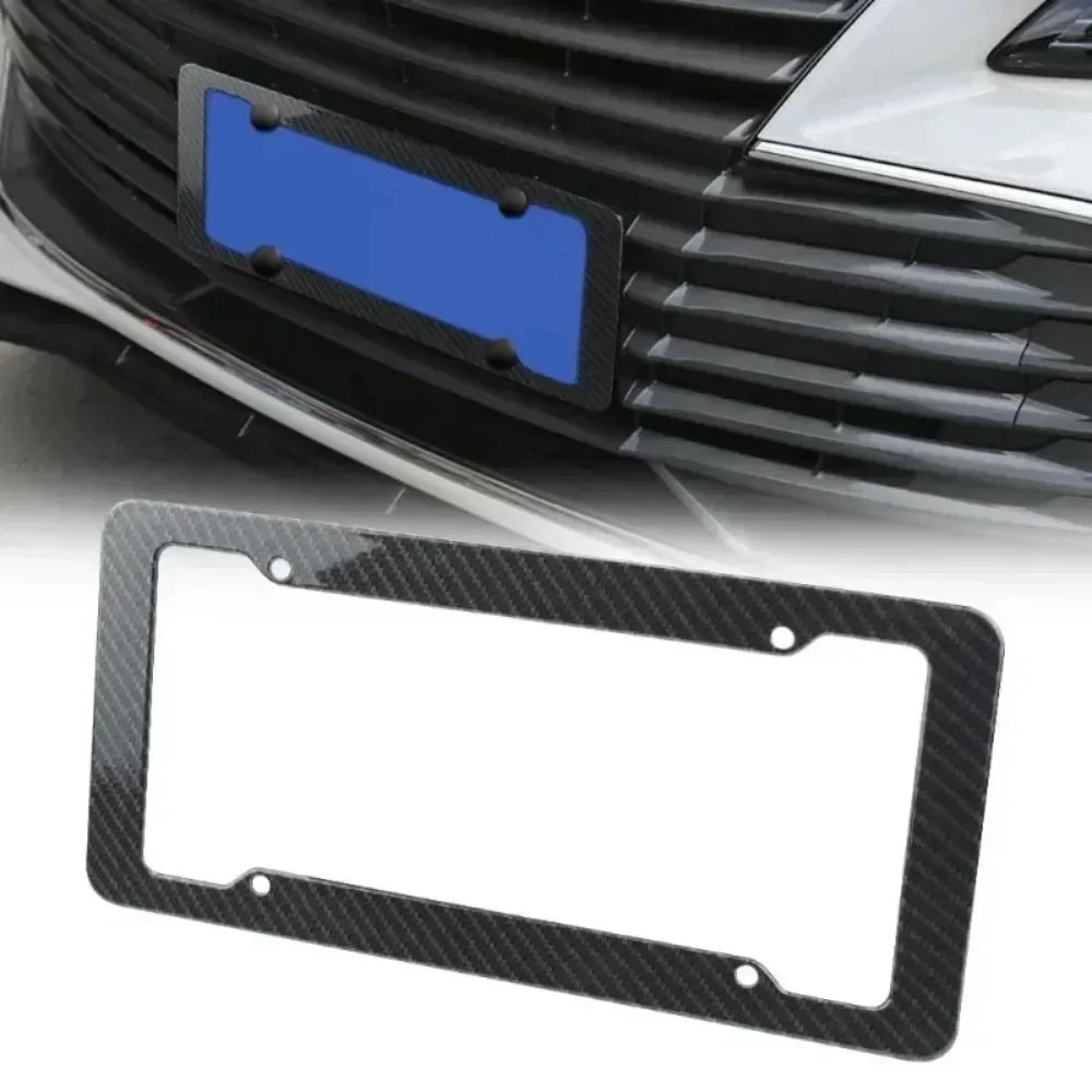 Black carbon fiber license plate frame with mounting hardware shown in context of a car grille.
