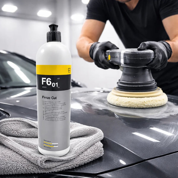 A bottle of F601 paint correction compound sits on a black car hood next to a cleaning cloth.