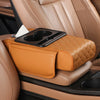 A leather car armrest cushion in tan color with a black tissue holder is shown inside a vehicle interior.