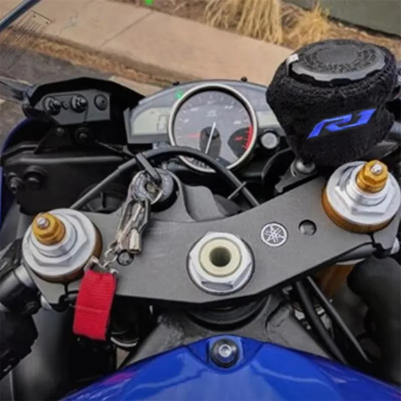 Gros plan du couvercle du réservoir de liquide de frein d'une moto et d'une clé USB attachée à la poignée.
