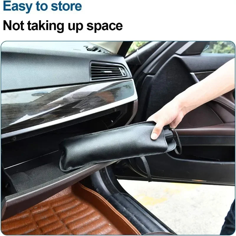 Eine Hand faltet einen schwarzen Stoff-Sonnenvorhang für die Windschutzscheibe eines Autos.