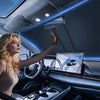 A woman is adjusting a heavy-duty portable car sunshade on the interior of a car.