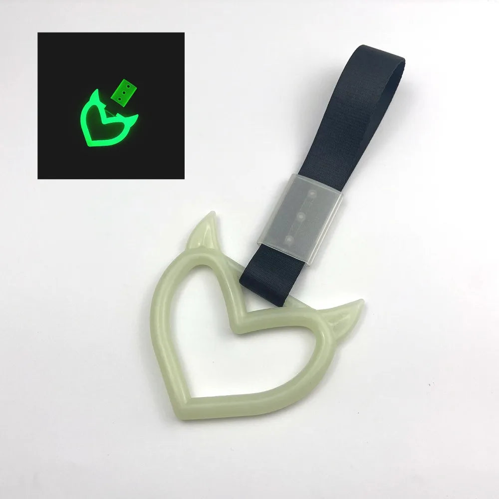 A light green holographic heart-shaped car handle accessory attached to a black strap.