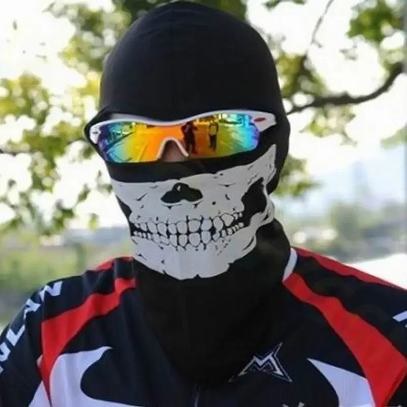 Une personne portant un balaclava noir avec un crâne blanc et des lunettes à miroir, à l'extérieur.