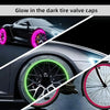 Gros plan d'une roue de voiture et de vélo montrant des bouchons de valve de pneu luminescents violet et vert.